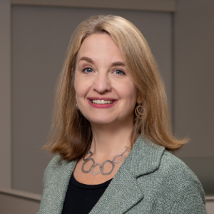 Image of a light skinned woman with blonde hair, wearing a blazer